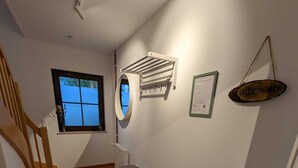 A staircase leading to a room with a window, a wall-mounted air conditioning unit, a small bench, and a welcome sign.