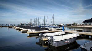 A marina with several sailboats docked, a control building, and a pier extending into the water. - Modern Houseboat in Offingawier With Terrace (Offingawier)