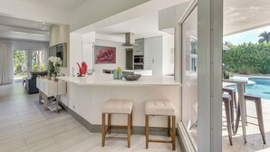A modern kitchen with a large island, bar stools, and a view of a swimming pool. - Relax in the Sun! Gem 1 Mi to Las Olas Beach (Fort Lauderdale)
