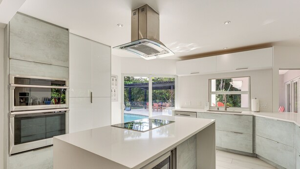 A modern kitchen with a central island, built-in oven, and a large window overlooking a garden. - Relax in the Sun! Gem 1 Mi to Las Olas Beach (Fort Lauderdale)