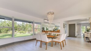 A spacious dining area with a large table and chairs, large windows, and a modern chandelier. - Relax in the Sun! Gem 1 Mi to Las Olas Beach (Fort Lauderdale)