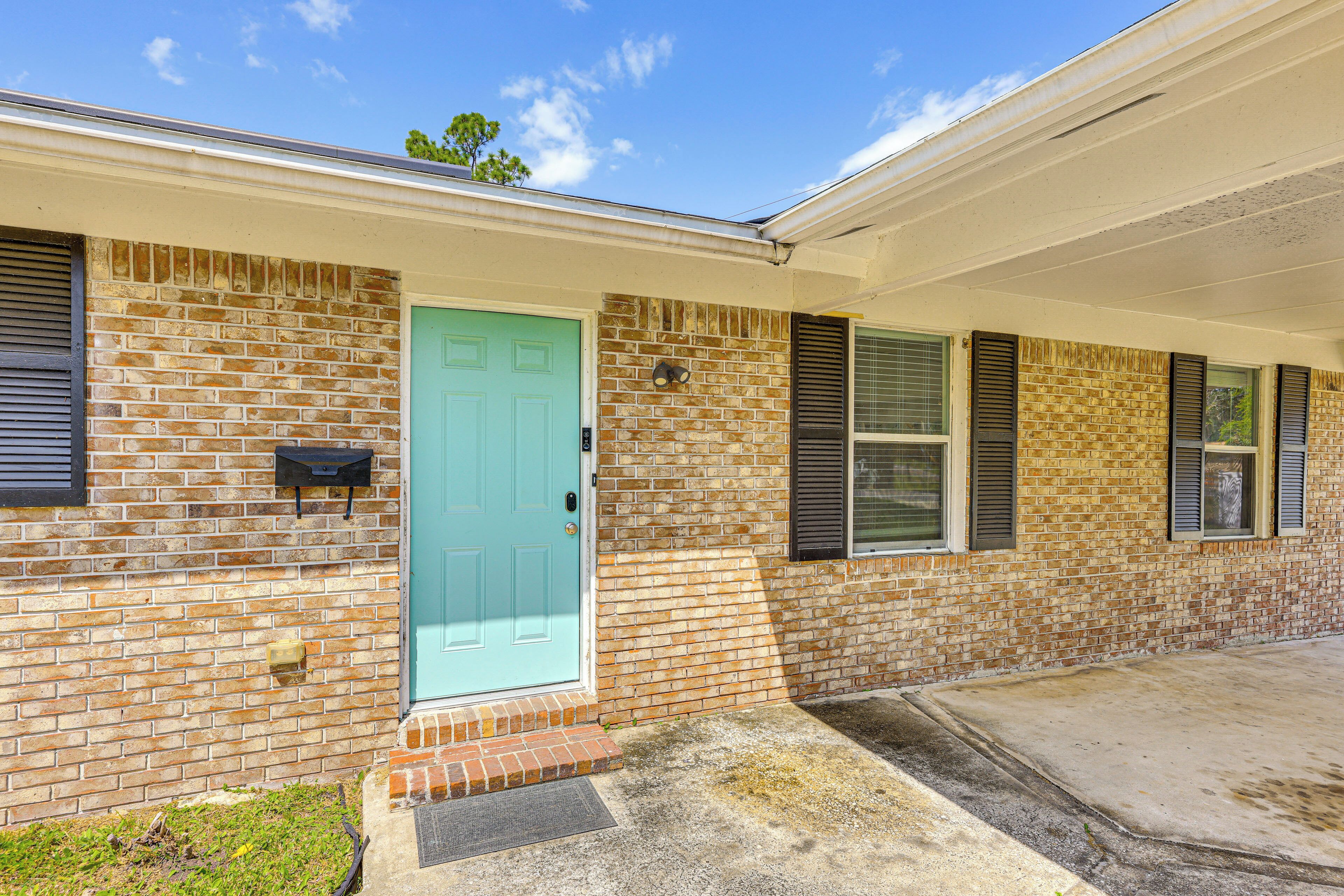 A single-story brick house with a light blue door, a small front porch, and a covered entryway.