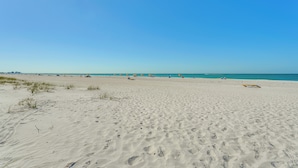 Ampia spiaggia sabbiosa con cielo azzurro limpido.