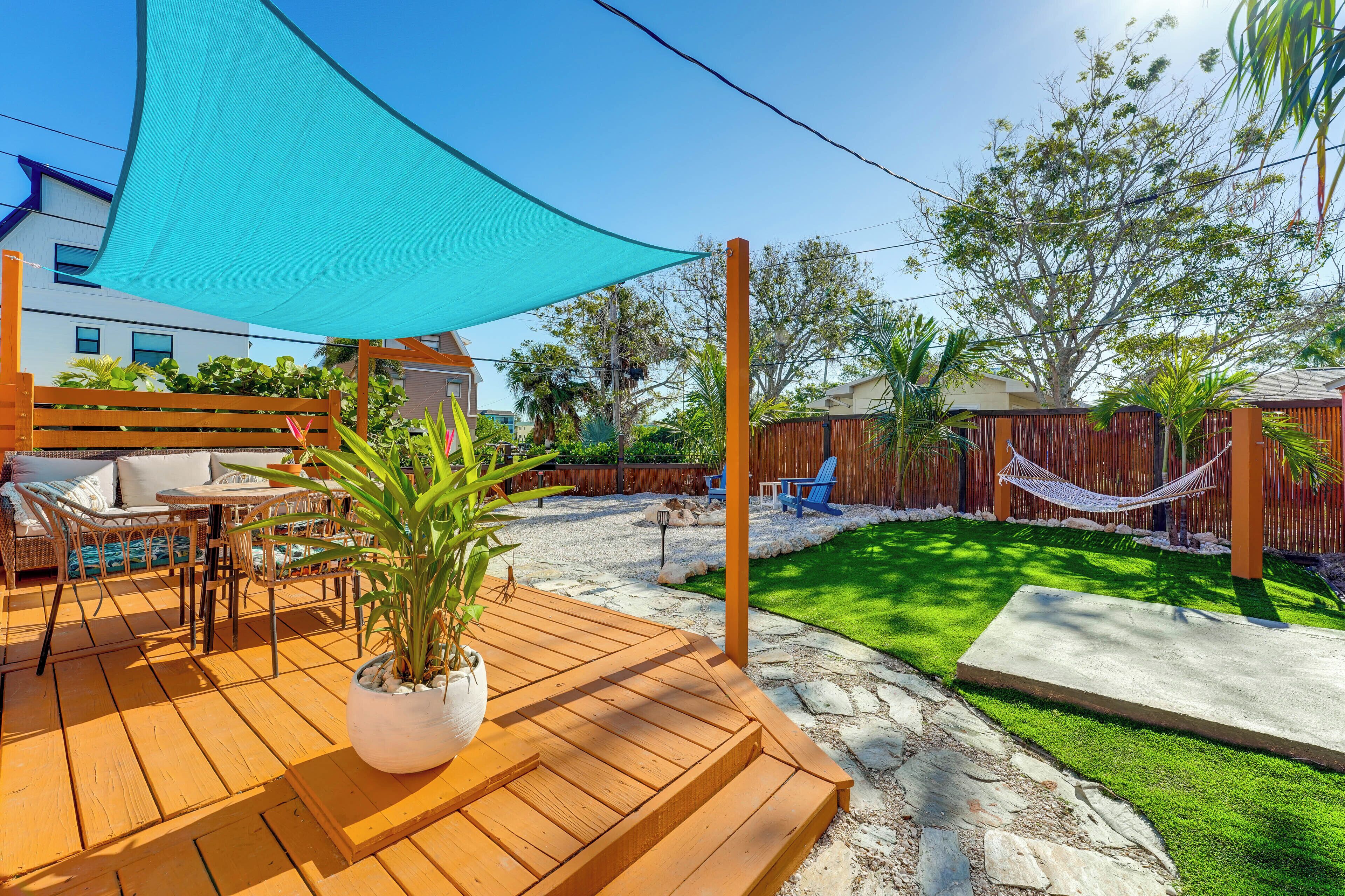 A wooden deck with outdoor furniture, a hammock, and a well-maintained lawn.