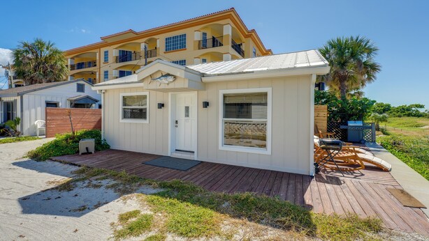 A beachfront property with a white building, a wooden deck, and a large balcony. - Beachfront Bliss + Bbqs! Indian Rocks Beach Escape (Indian Rocks Beach)