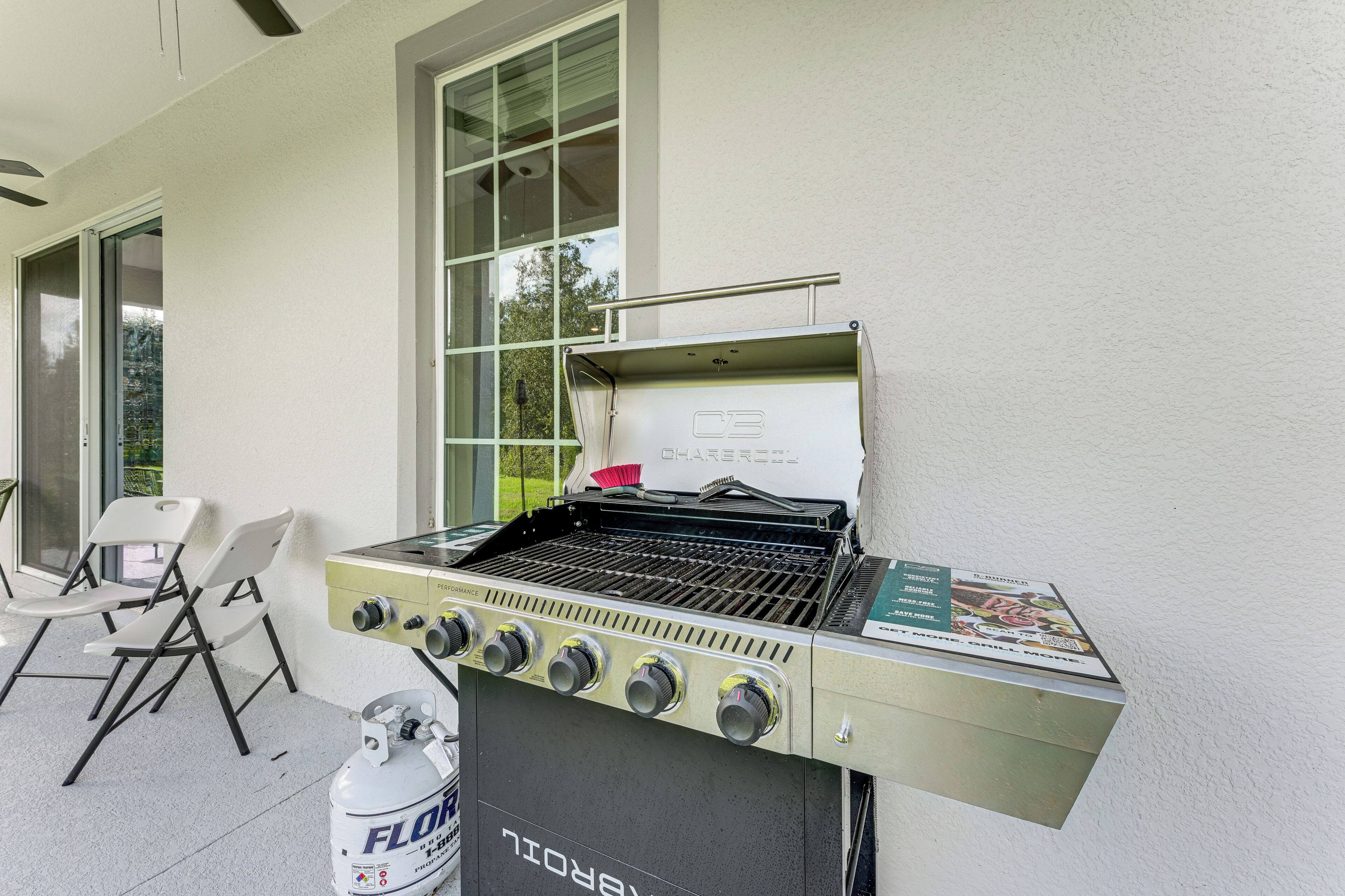A barbecue grill with four burners, a gas tank, and a grill cover.