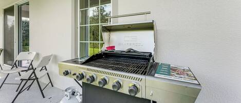 A barbecue grill with four burners, a gas tank, and a grill cover.
