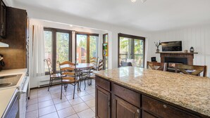 A kitchen with granite countertops, wooden cabinets, and a dining area with chairs and a table. - Inner Circle Retreat — Walk to Main Street, Pool and the Slopes (Breckenridge)