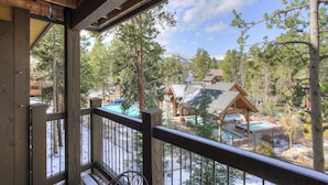 A wooden deck with a view of a resort area including a pool and cabins. - Inner Circle Retreat — Walk to Main Street, Pool and the Slopes (Breckenridge)