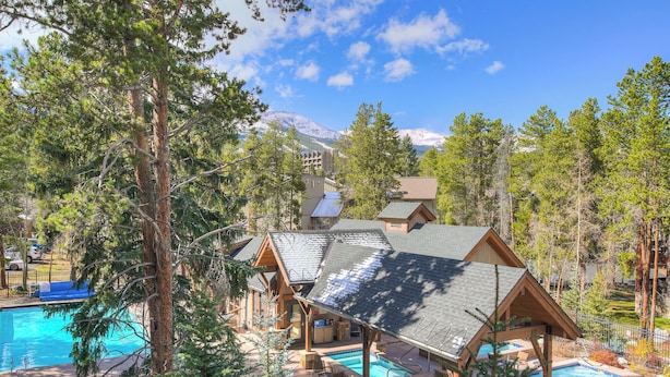 A lodge with a pool area, surrounded by trees and a mountain in the background. - Inner Circle Retreat — Walk to Main Street, Pool and the Slopes (Breckenridge)