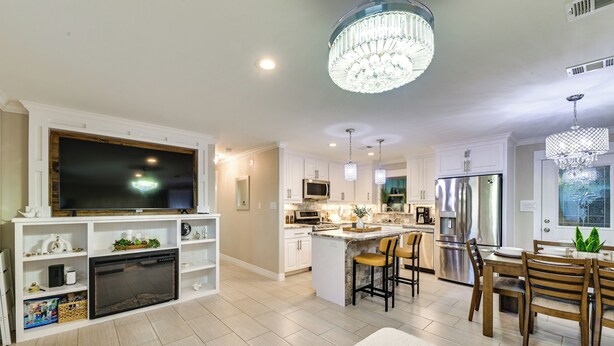 A modern kitchen with a central island, built-in appliances, and a dining area with wooden chairs and a chandelier. - Walk to Frisco Commons Park: Modern Home w/ Patio (Frisco)