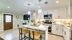 A modern kitchen with white cabinets, a marble island, and pendant lighting. - Walk to Frisco Commons Park: Modern Home w/ Patio (Frisco)