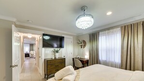 A hotel room with a large bed, a desk, a television, and a chandelier. - Walk to Frisco Commons Park: Modern Home w/ Patio (Frisco)