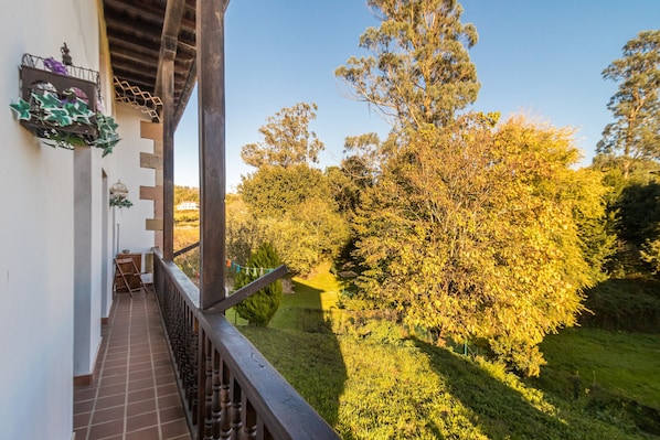 A balcony with a view of a garden and trees.