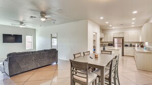 A modern kitchen with white cabinets, a central island, and a dining area with a table and chairs. - Hike & Explore: Apt 3 Mi to Lake Havasu & Dtwn! (Lake Havasu City)