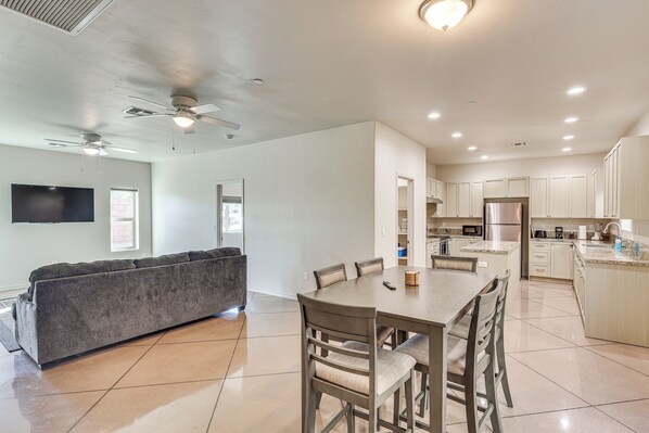 A modern kitchen with white cabinets, a central island, and a dining area with a table and chairs. - Hike & Explore: Apt 3 Mi to Lake Havasu & Dtwn! (Lake Havasu City)