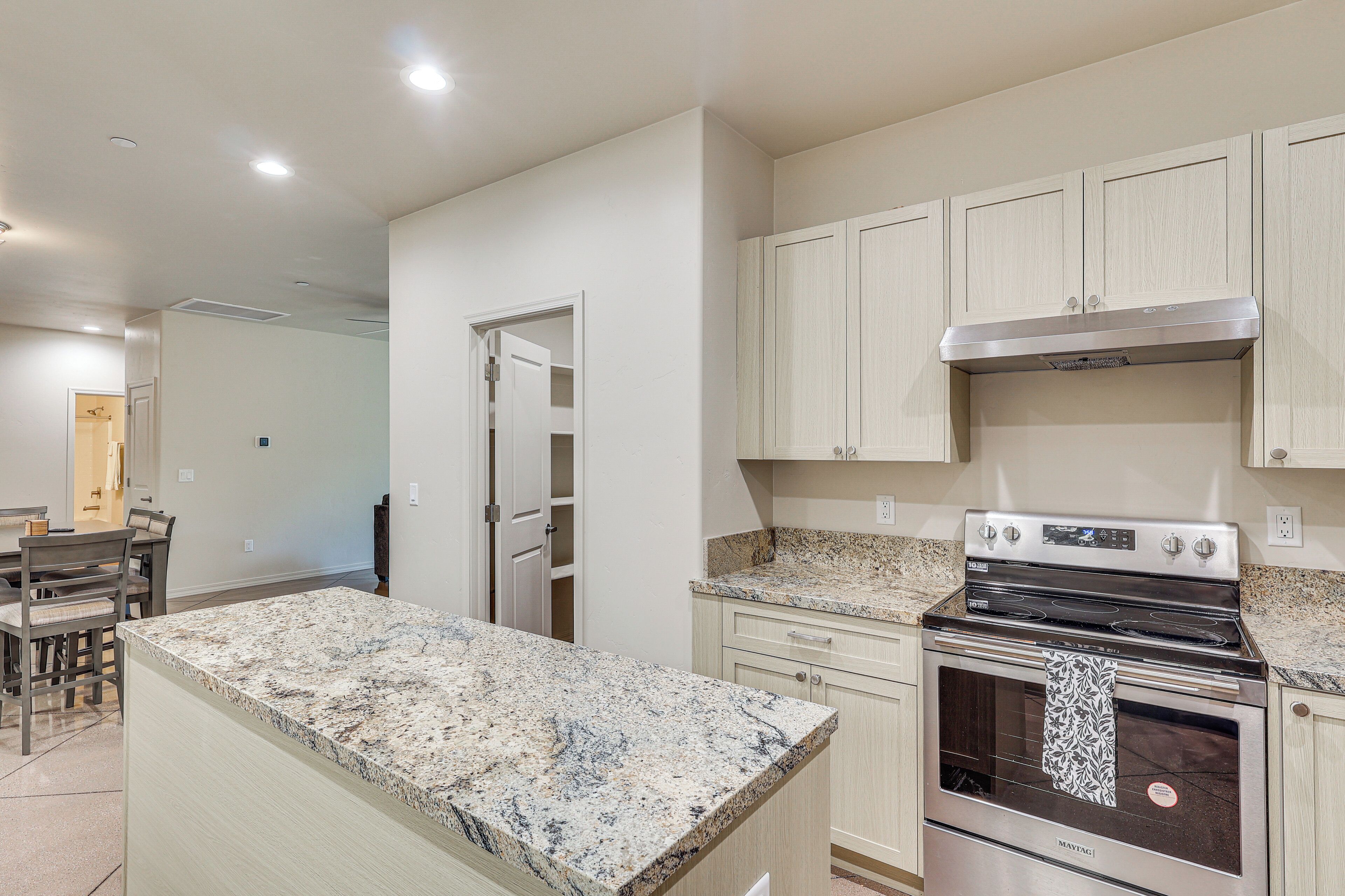 A kitchen with a granite countertop, stainless steel appliances, and light-colored cabinetry.