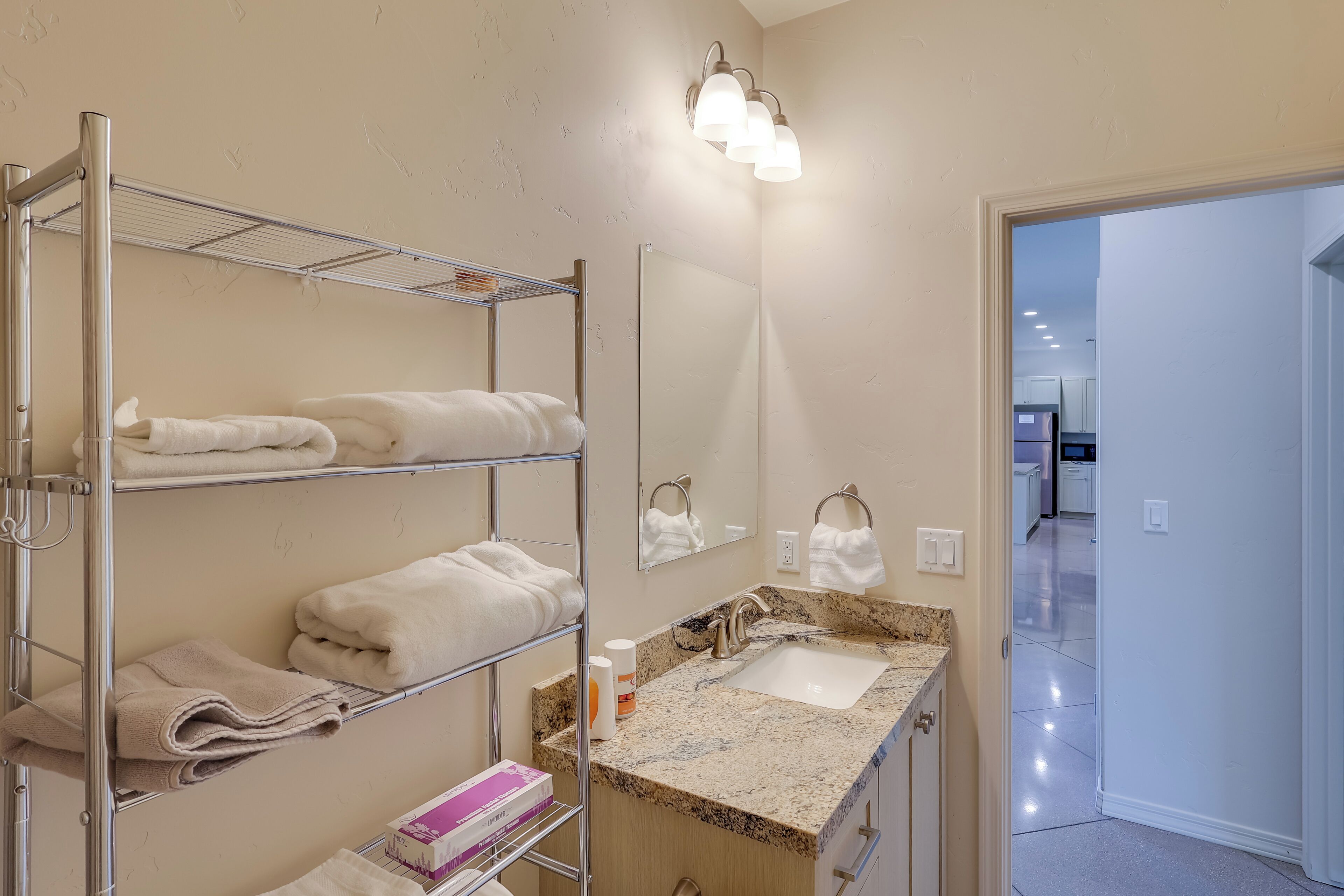 Un baño con lavamanos, espejo, toalleros y zona de ducha.
