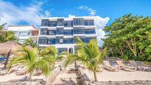 A modern hotel with a multi-story structure, a beachside location, and a pool area with sun loungers.