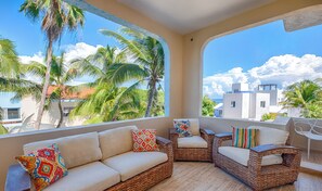 A balcony with wicker furniture, including a sofa and armchairs, with colorful cushions. - Oceanfront Gem! Remodeled Condo with Stunning Views of Half Moon Bay (Akumal)