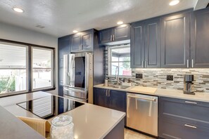 A modern kitchen with dark cabinets, stainless steel appliances, and a large island. - Great Outdoor Space! Family Home in SLC Suburbs (Midvale)