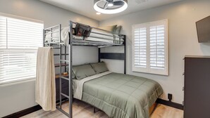 A bunk bed room with a green bedspread, a ladder, and a ceiling fan.