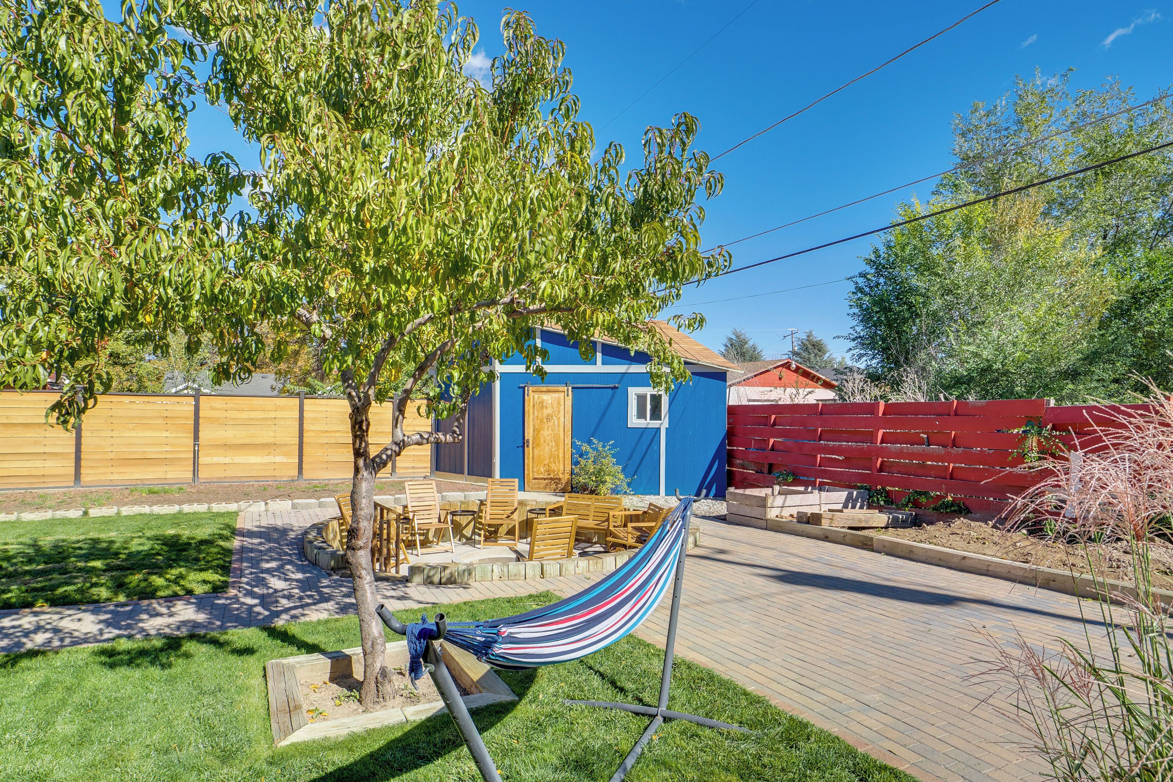 A backyard with a hammock, a wooden fence, and a blue building.