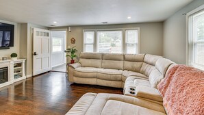 A living room with a sectional sofa, a fireplace, and a large window with blinds. - Stay & Play in Plymouth: Spacious Home w/ Yard (Plymouth)