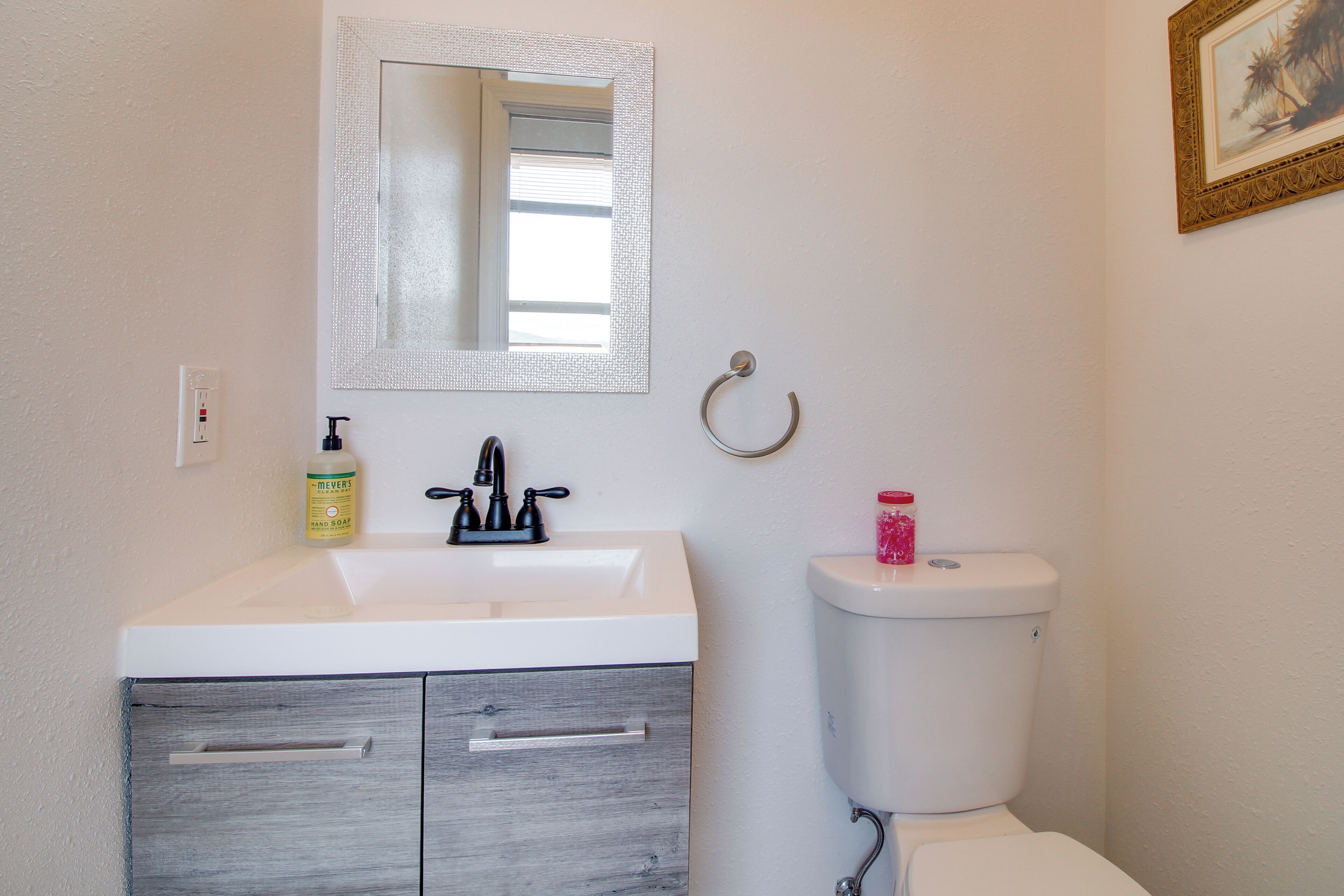 Een badkamer met een wit wastafel, een spiegel, een toilet en een handdoekhouder.
