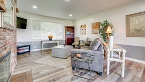 A modern living room with a fireplace, a grey sofa, a coffee table, and a bookshelf. - Yakima Wine Country Haven: Near Hiking & Fishing! (Yakima)