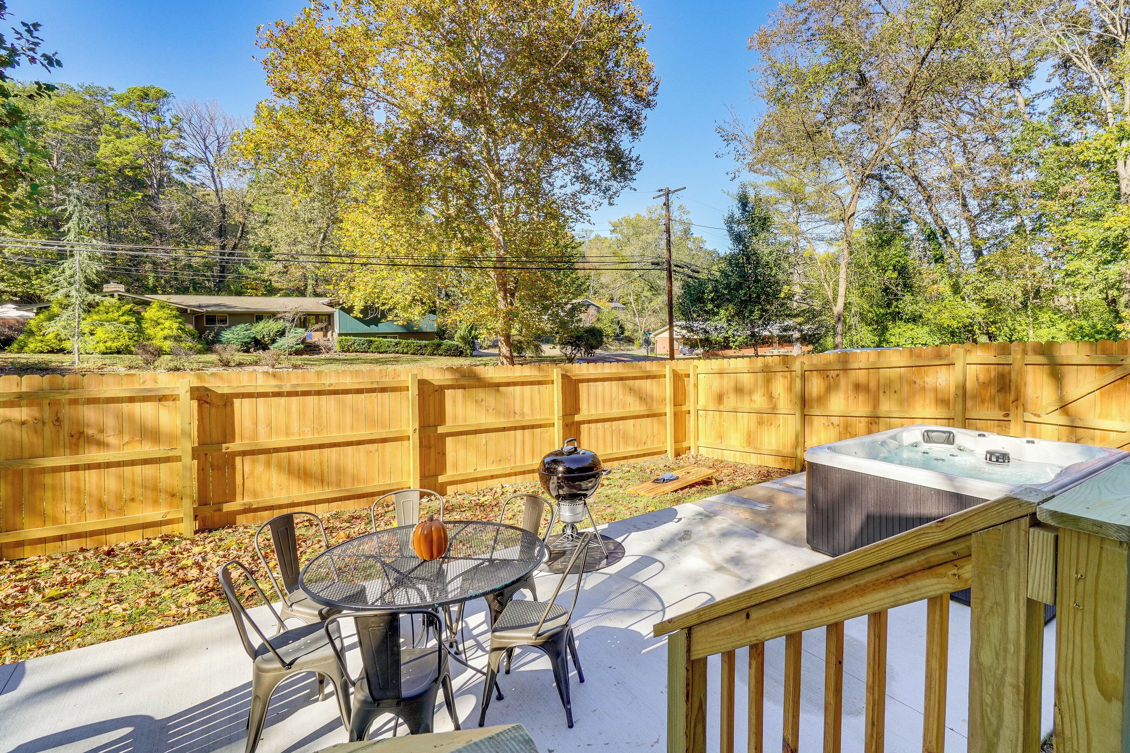 A backyard with a wooden deck, a hot tub, and a barbecue grill.