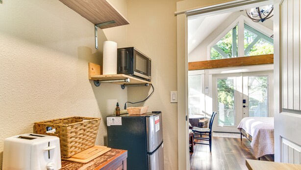Una cocina compacta con tostadora, microondas y refrigerador, una mesa de madera y una cesta.