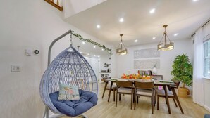 Un comedor con una silla colgante, mesa de madera, sillas y una planta en maceta.