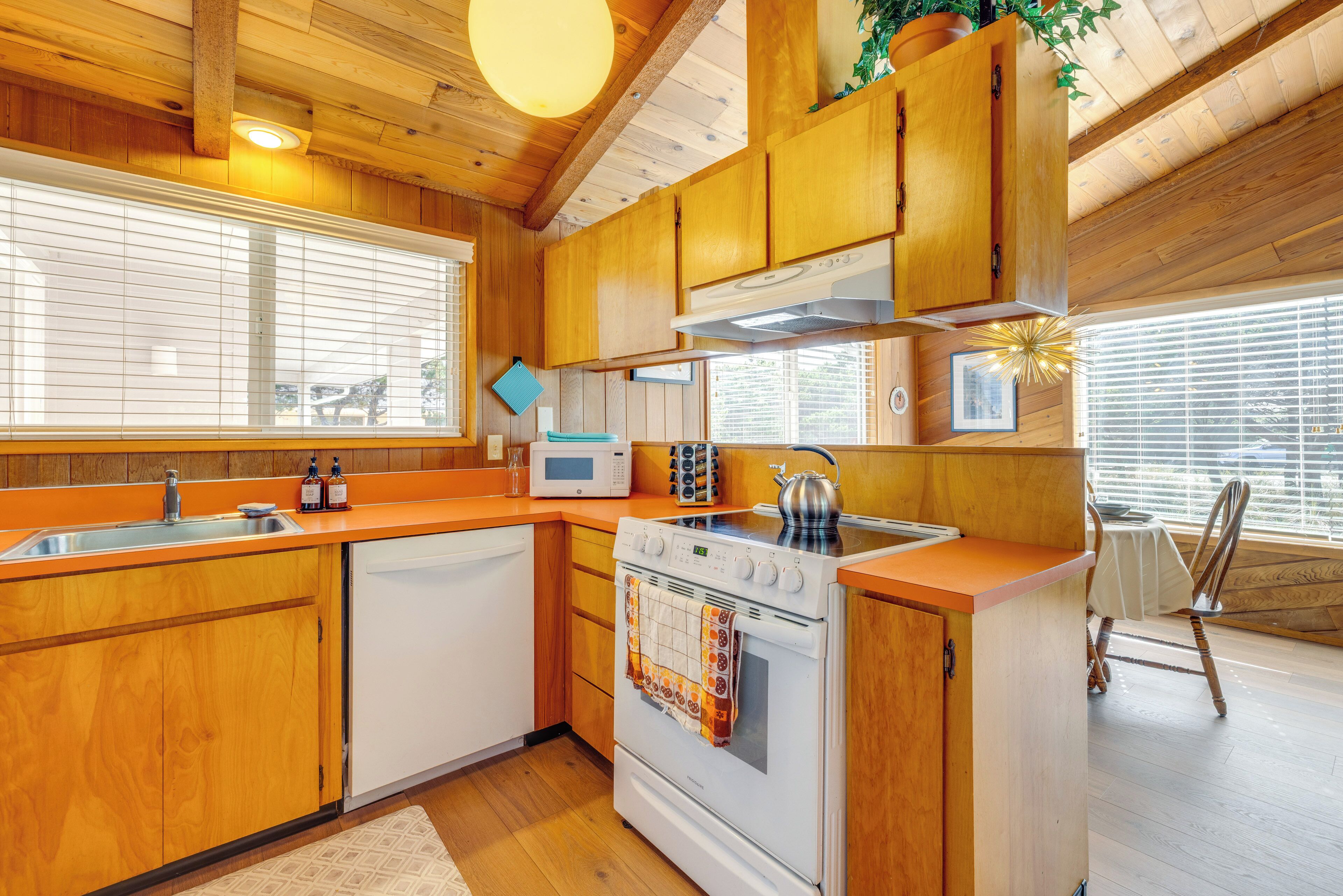 A kitchen with wooden cabinets, a microwave, an oven, and a sink.