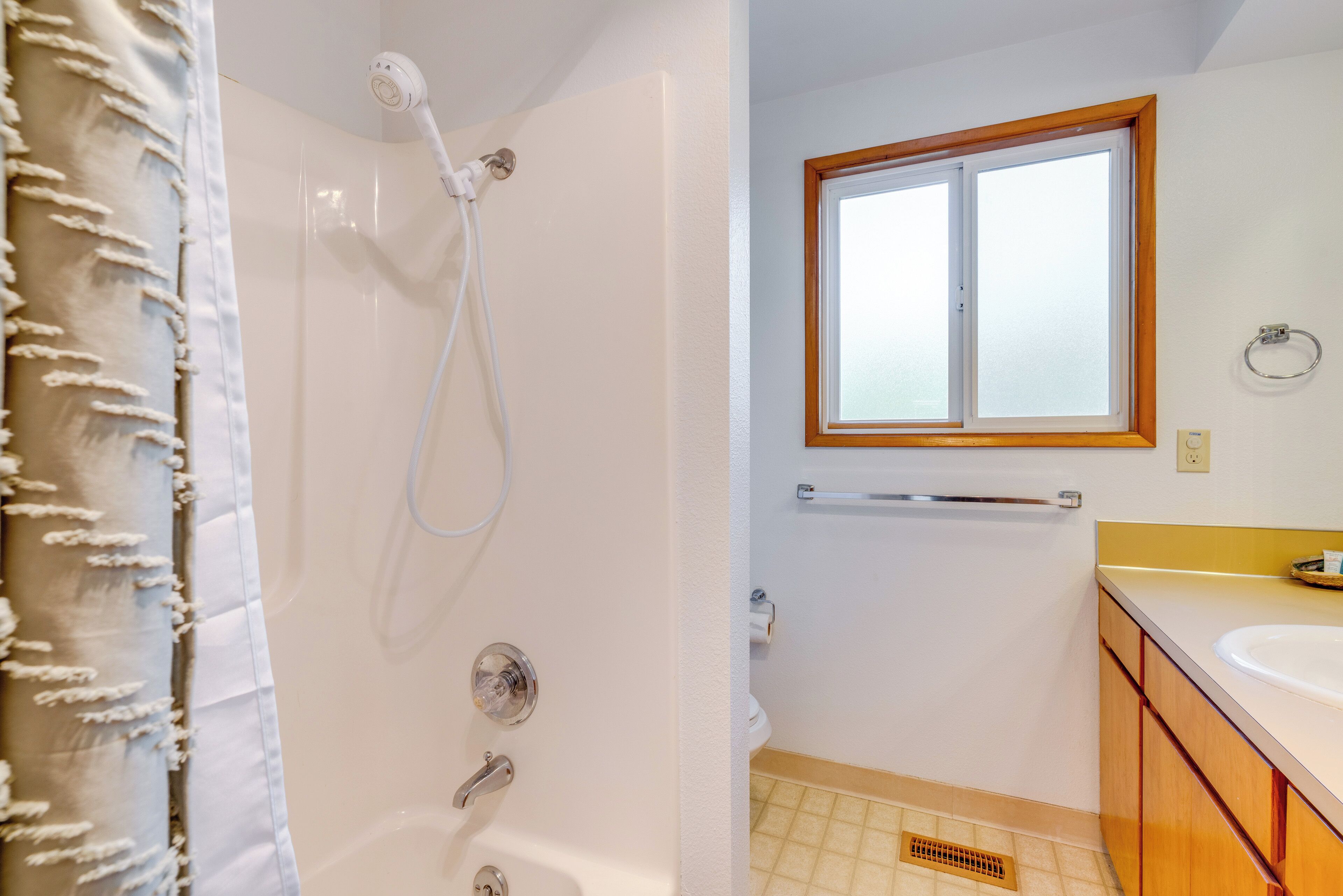 Une salle de bain avec une douche, une fenêtre, un lavabo et des meubles en bois.