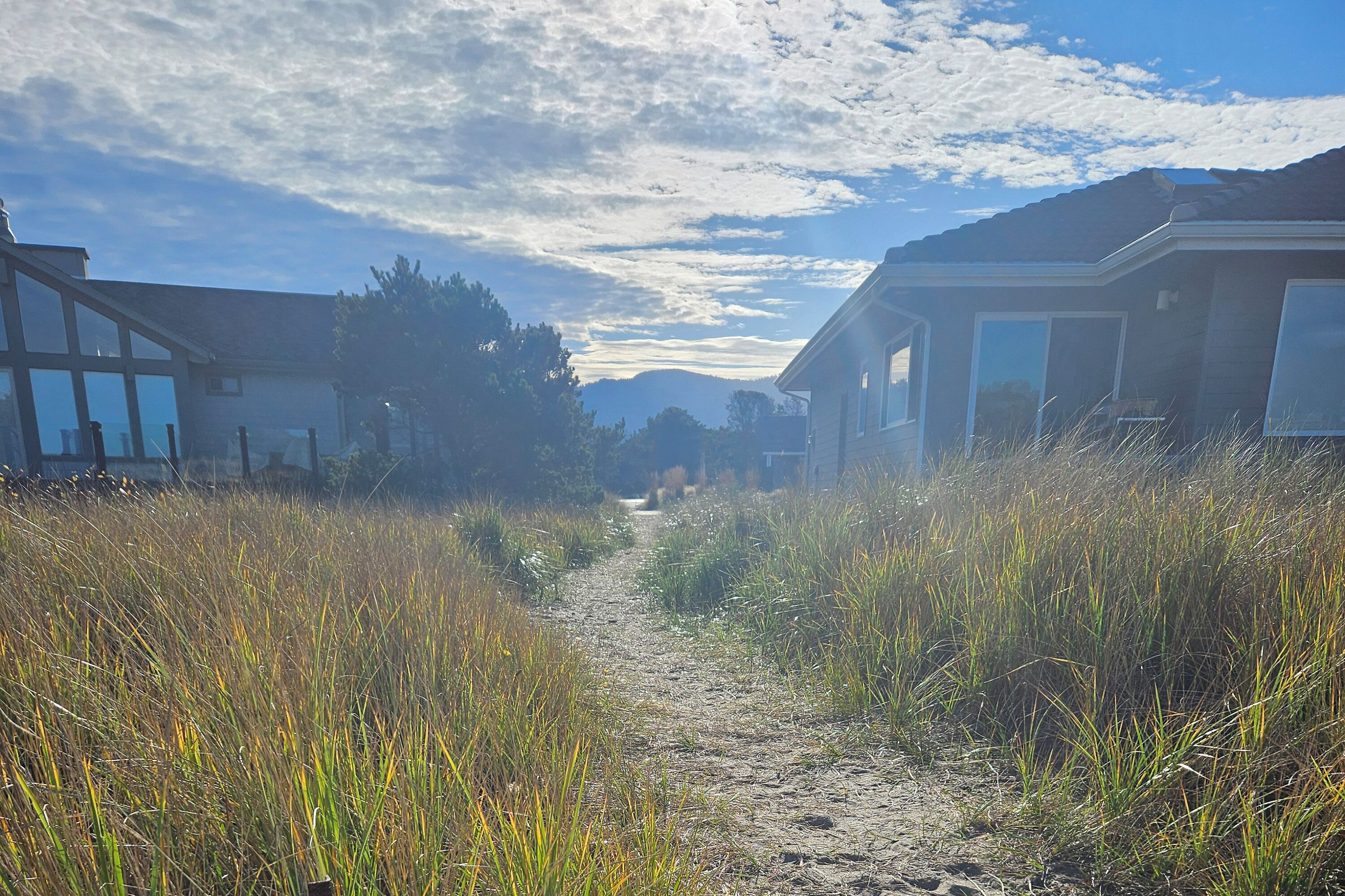 A pathway between two buildings with a clear sky and distant mountains.