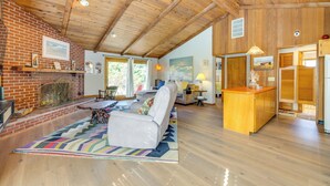 A spacious living room with a fireplace, a sofa, and a wooden ceiling.