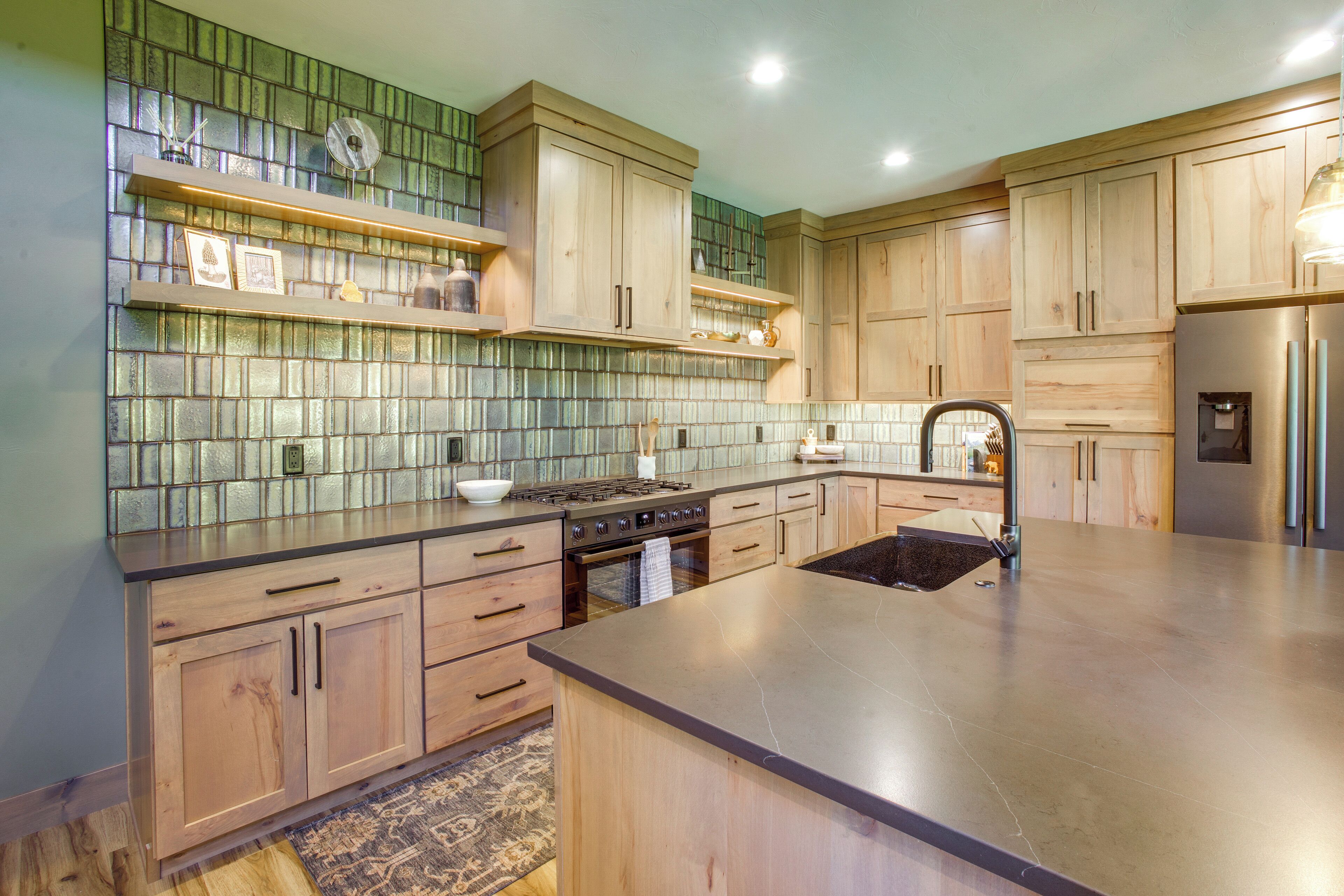 A modern kitchen with wooden cabinets, a large island, and a tiled backsplash.