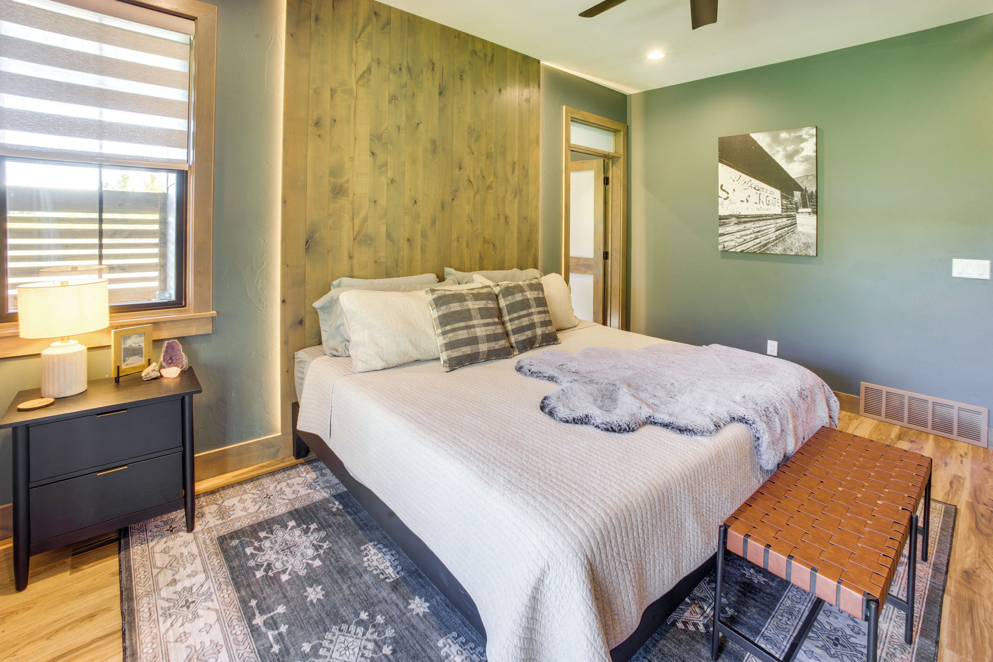A bedroom with a bed, bedside table, lamp, and a wall-mounted artwork.