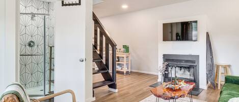 A living room with a fireplace, a staircase, and a green sofa.