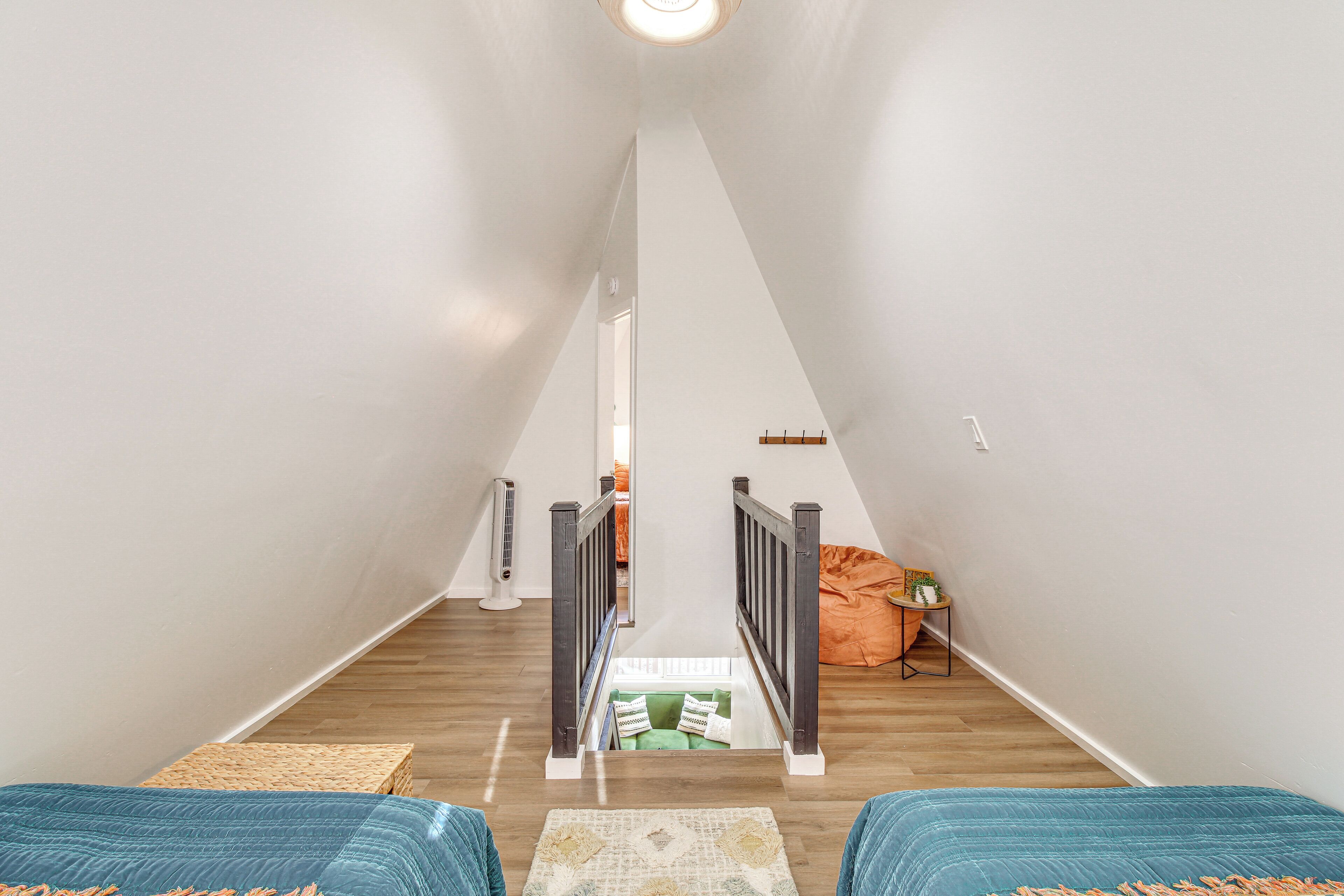 A narrow attic bedroom with a sloped ceiling, wooden flooring, and two beds with blue bedding.