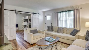 A living room with a sofa set, a coffee table, and a sliding door leading to a storage area. - Game Room, Yard: Home 3 Mi to Daytona Beach! (Holly Hill)