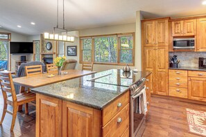 A spacious kitchen with wooden cabinets, a granite countertop, and a large island. - Woodland Gem w/ Pool Access: Linville Land Harbor (Newland)