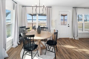 A dining area with a round table, black chairs, a chandelier, and a view of the outdoors. - Lakefront Gem w/ Hot Tub & Game Room in Graford (Graford)