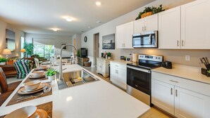 A modern kitchen with white cabinets, a stainless steel stove, and a microwave.