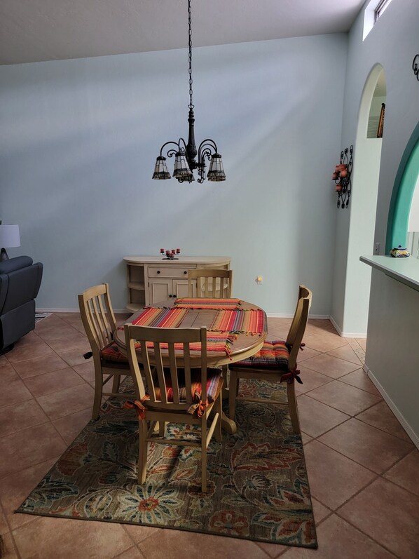 Un coin repas avec une table ronde, des chaises, un tapis à motifs et un lustre.