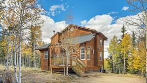 A wooden cabin with a porch and stairs, surrounded by trees with autumn foliage. - Private Wooded Escape w/ Scenic Decks in Jefferson (Jefferson)