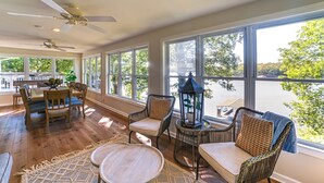 A spacious room with large windows, a ceiling fan, wicker furniture, and a view of a body of water. - Spacious Kentucky Lake Escape w/ Dock & Views (Benton)