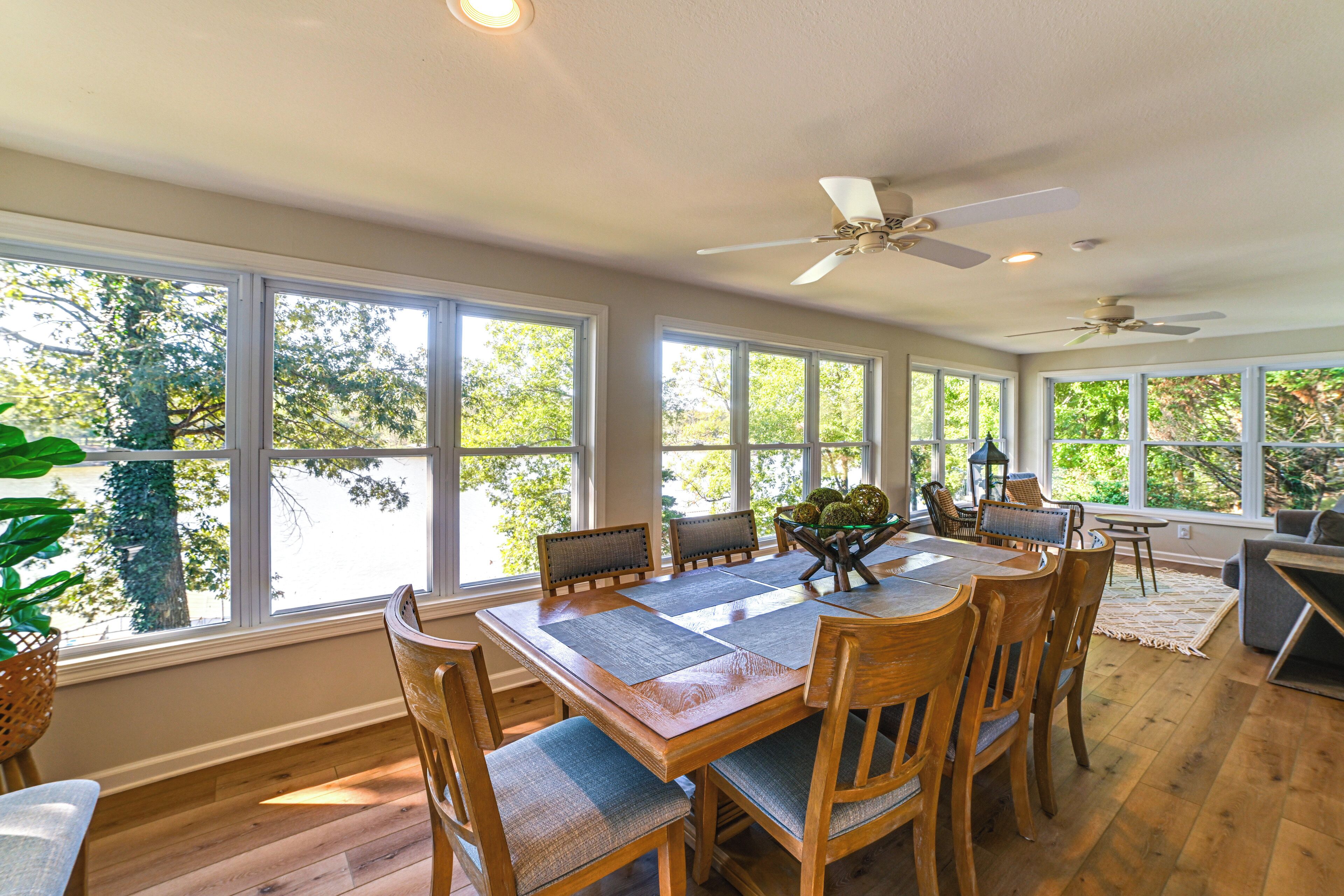 A spacious dining area with a large wooden table, multiple chairs, and a ceiling fan.