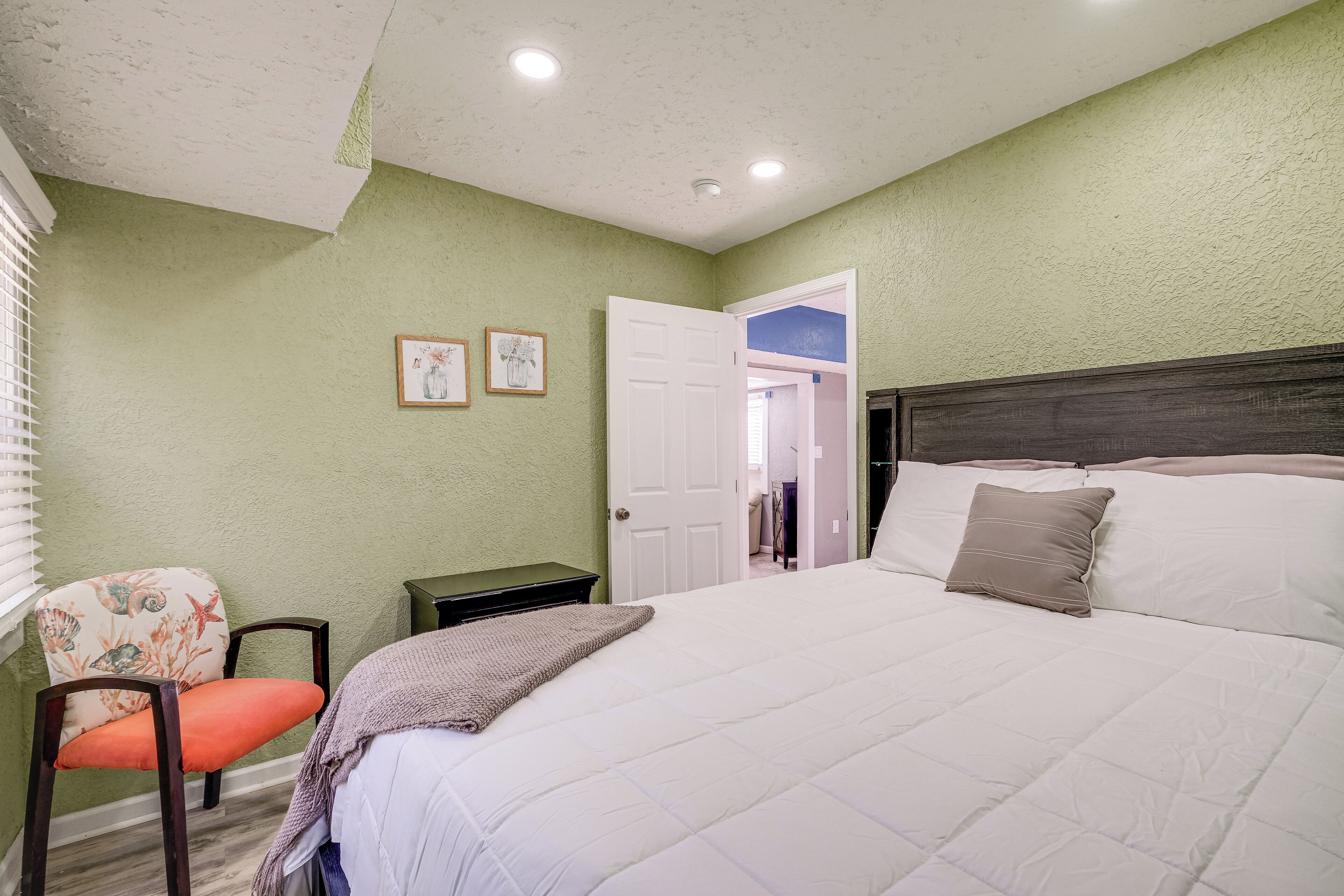 A bedroom with a bed, a chair, and a nightstand.